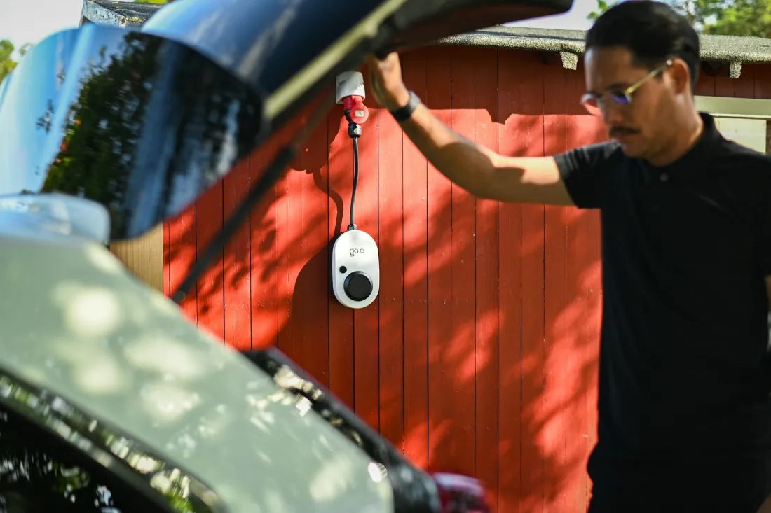 Elbil som laddas i en laddbox monterad på en husvägg
